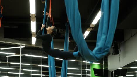 attractive woman doing aero yoga stretching exercises in hammocks at fitness studio. healthy lifestyle for female. workout gym