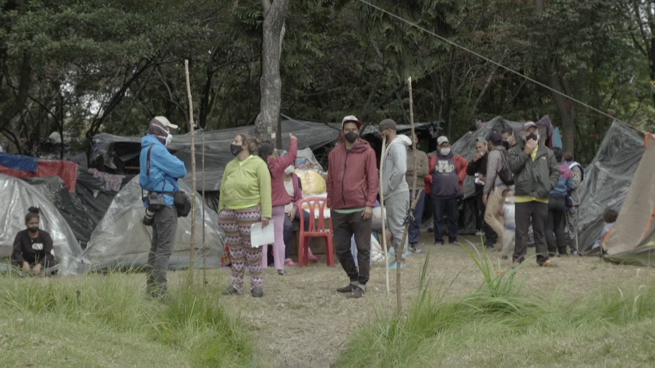 People gathered in an informal settlement with makeshift shelters
