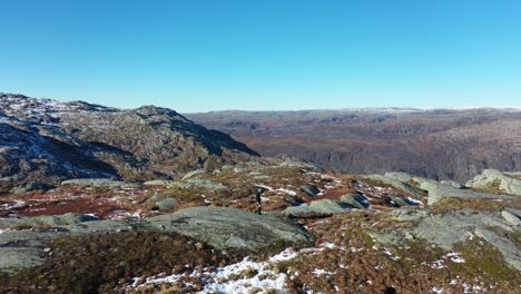 landscape photographer walking in mountain at fall season while carrying camera with telephoto lens in hand - aerial following person with blue sky background - first snow seen on ground norway