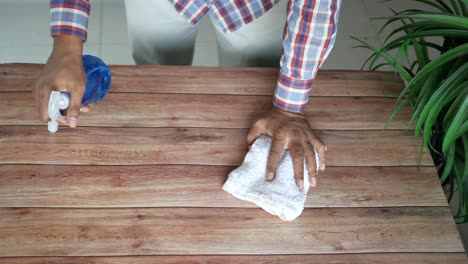 person cleaning a wooden table