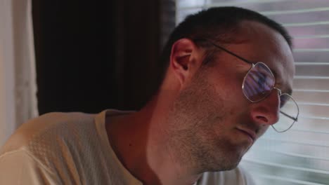 depressed man sitting near a window thinking deeply