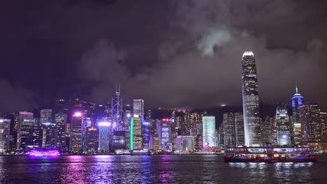star ferry sailing in victoria harbour in hong kong at night with city skyline