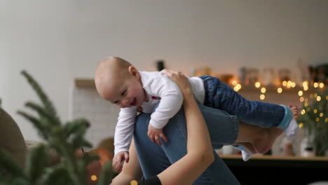 Concepto-De-Familia,-Maternidad-Y-Personas:-Madre-Feliz-Besando-Al-Pequeño-Bebé-Durante-Las-Vacaciones-Luces-De-Fondo