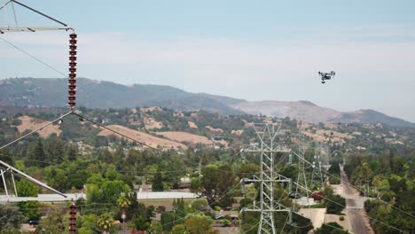drone realizando una inspección aérea de la torre de transmisión con montañas en el fondo