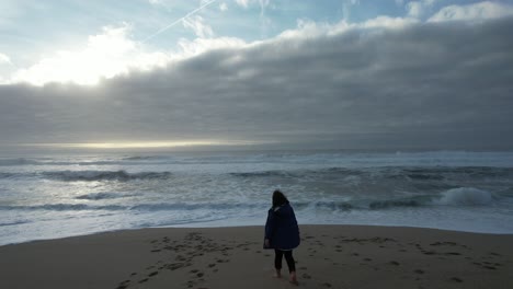 niña en la playa en el día de invierno con nubes de tormenta en el cielo