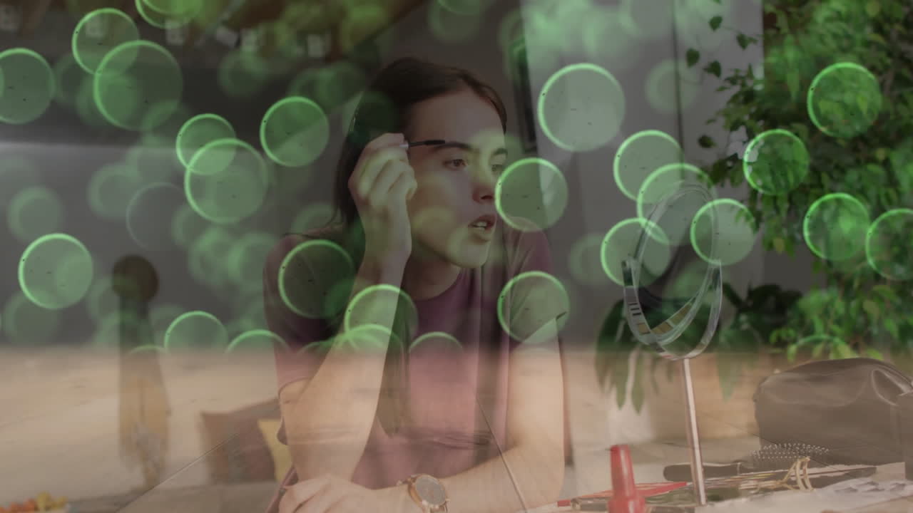Woman applying eyebrow makeup at wooden desk, showcasing beauty tutorial with green bokeh overlays