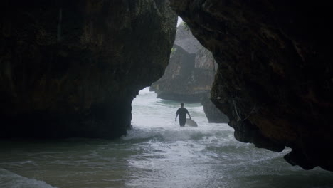 hombre con tabla de surf blanca en las manos extiende los brazos como una gran ola rueda en