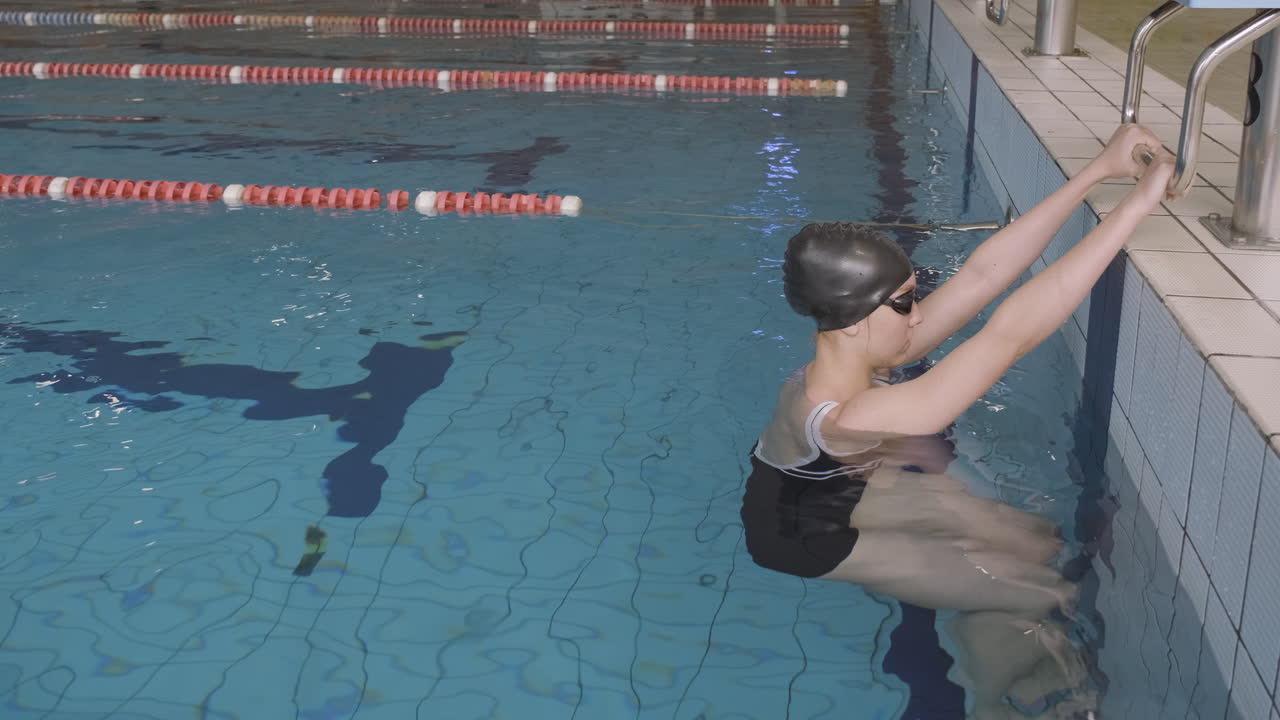 Side Shot Of Young Female Swimmer Starts Backstroke In Indoor Pool