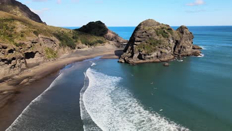 Fliegen-Neben-Der-Felswand-Am-Schwarzen-Sandstrand