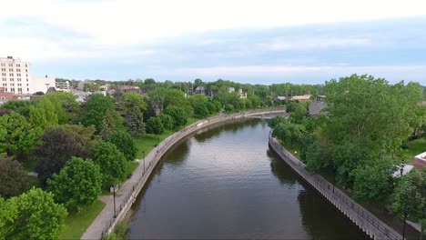 A-drone-flies-over-the-Flint-River-in-downtown-Flint,-Michigan-at-dusk-in-summer