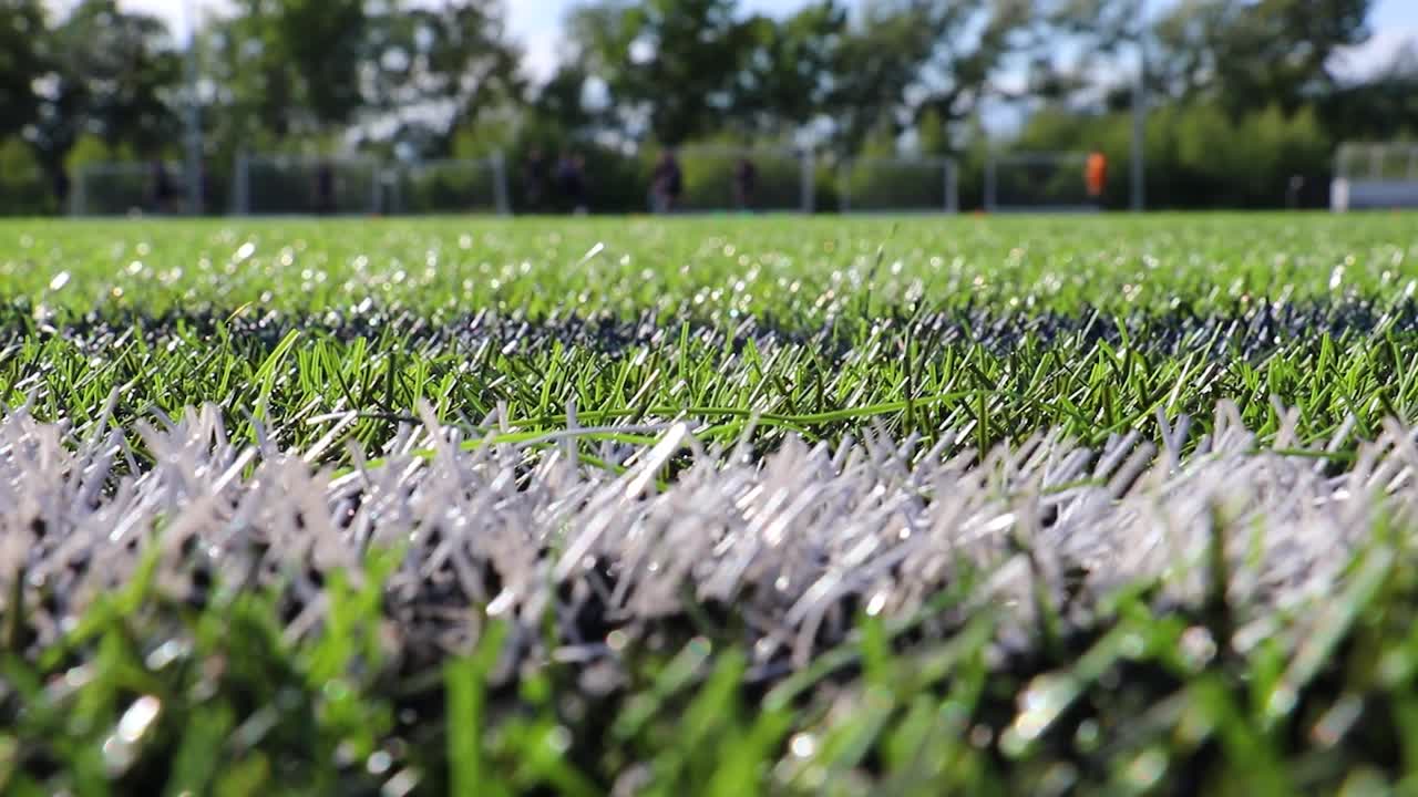 Close up of white line on artificial grass football pitch. Static.