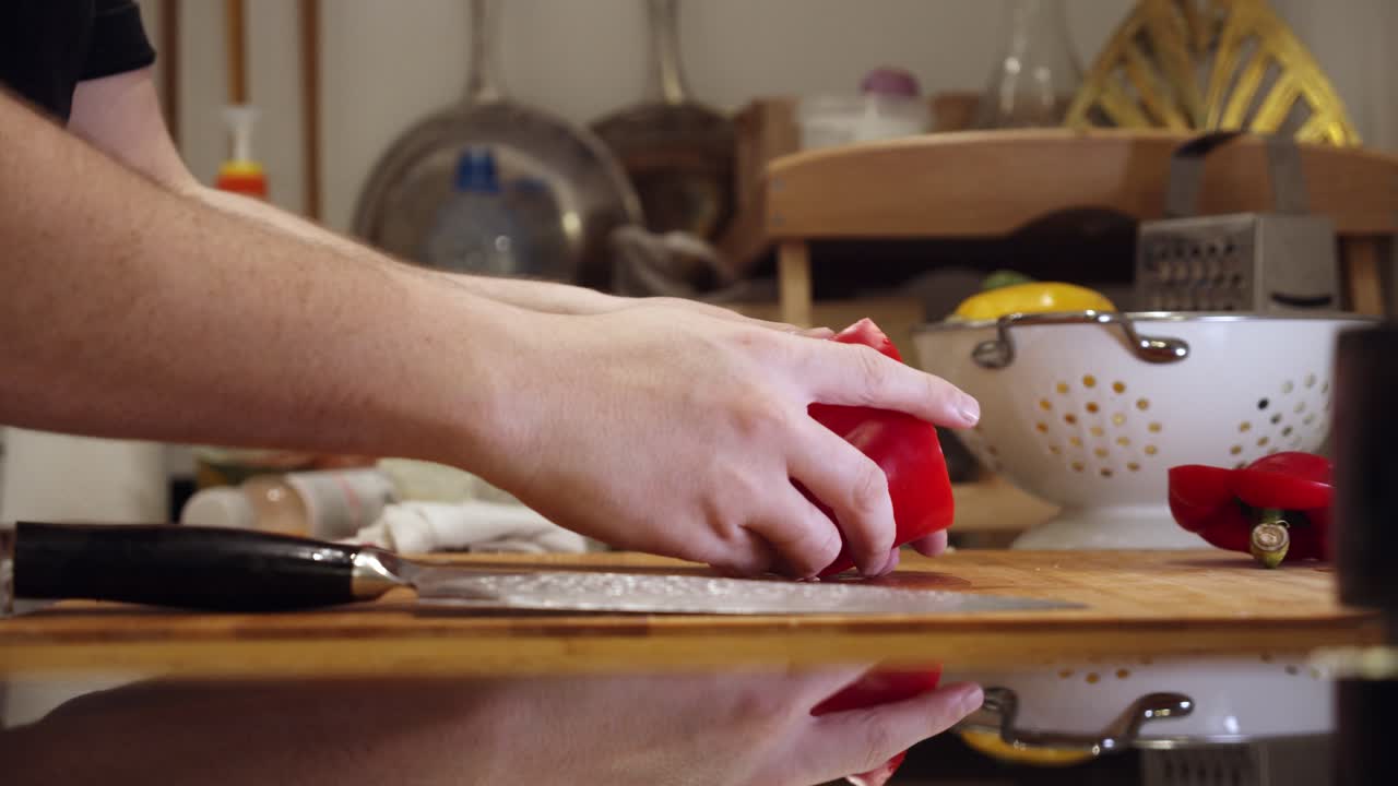 chef corta pimiento rojo grande en la tabla de cortar, en la cocina