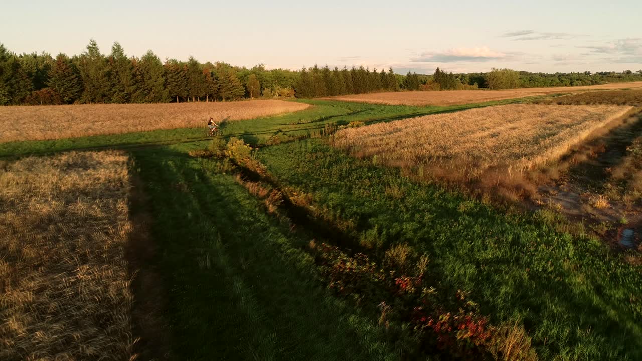 A girl does biking in a farm field during the autumn