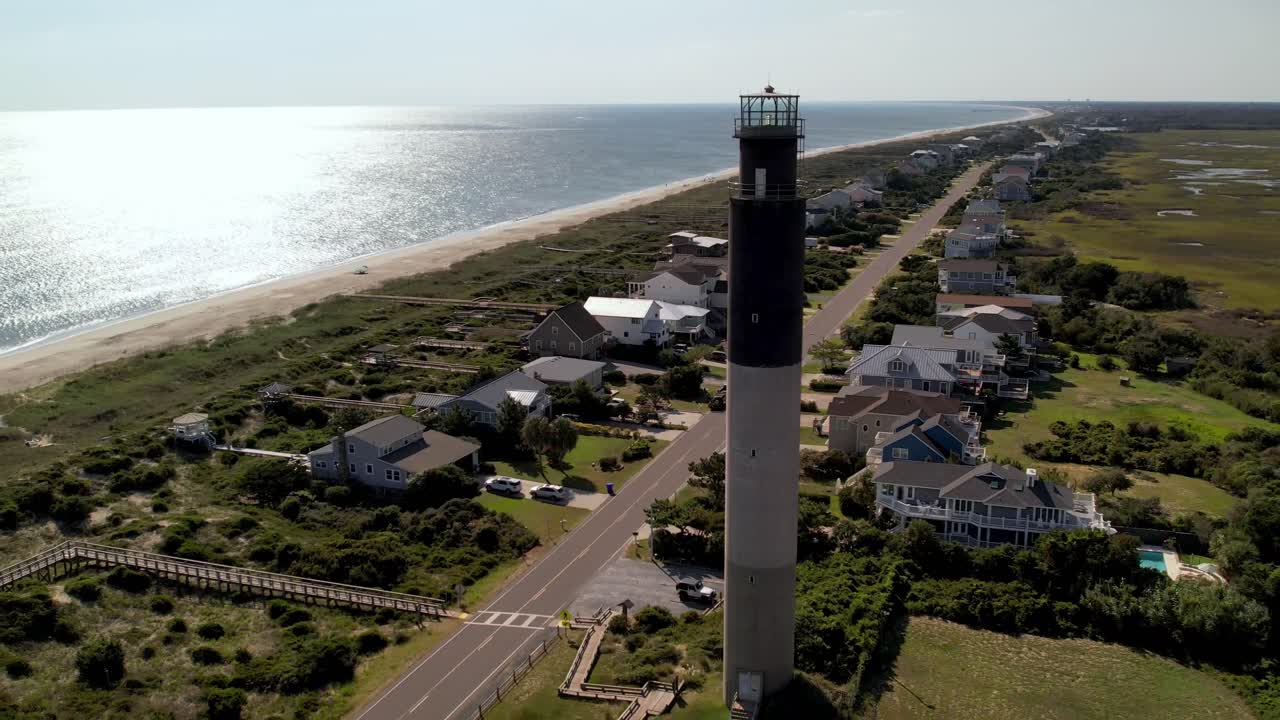 Carrellata aerea all'indietro dal faro di Oak Island a Caswell Beach, Carolina del Nord.