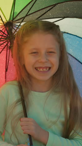 child plays with multicolored umbrella. girl each twirl of parasol seems to create ripples of joy casting aside any gloom rain brings. riverside retreat