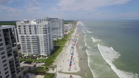 Flying-near-high-rise-resorts-next-to-the-ocean-on-a-bright-sunny-day