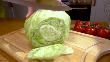 knife cuts salad, lettuce on wooden board slow motion with rotation tracking shot.