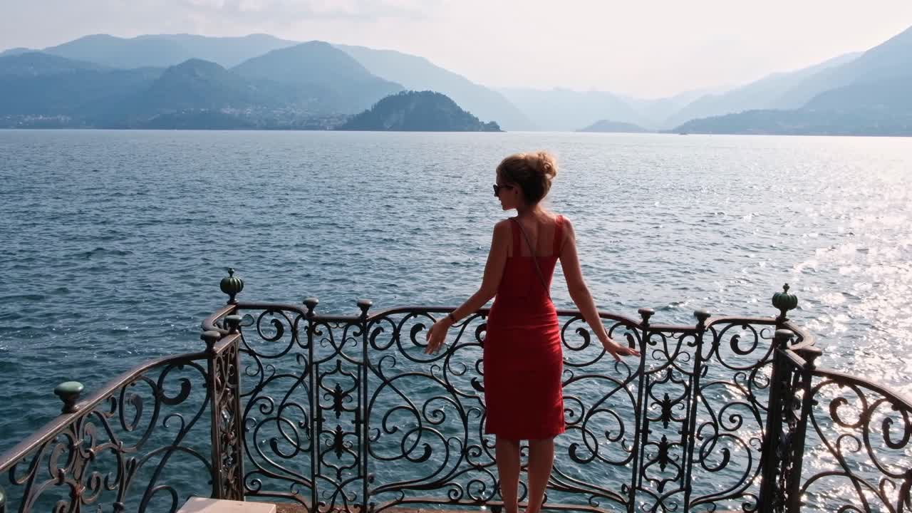 LOMBARDY, ITALY - AUGUST 02, 2018: Scenic shot of a woman admiring the beauty of Como lake and mountains