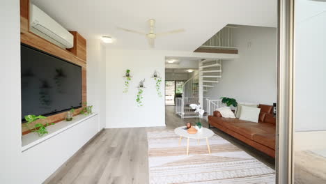 reveal of loft style lounge room with spiral staircase and brown stained wood accent wall matching seating and plants