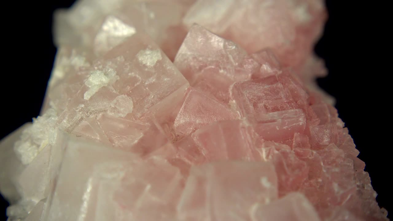 rotación sin problemas de un mineral rosado (halita rosada) frente a un fondo negro