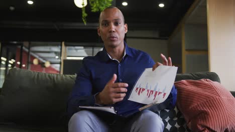 mixed race businessman having video chat and discussing paperwork in office