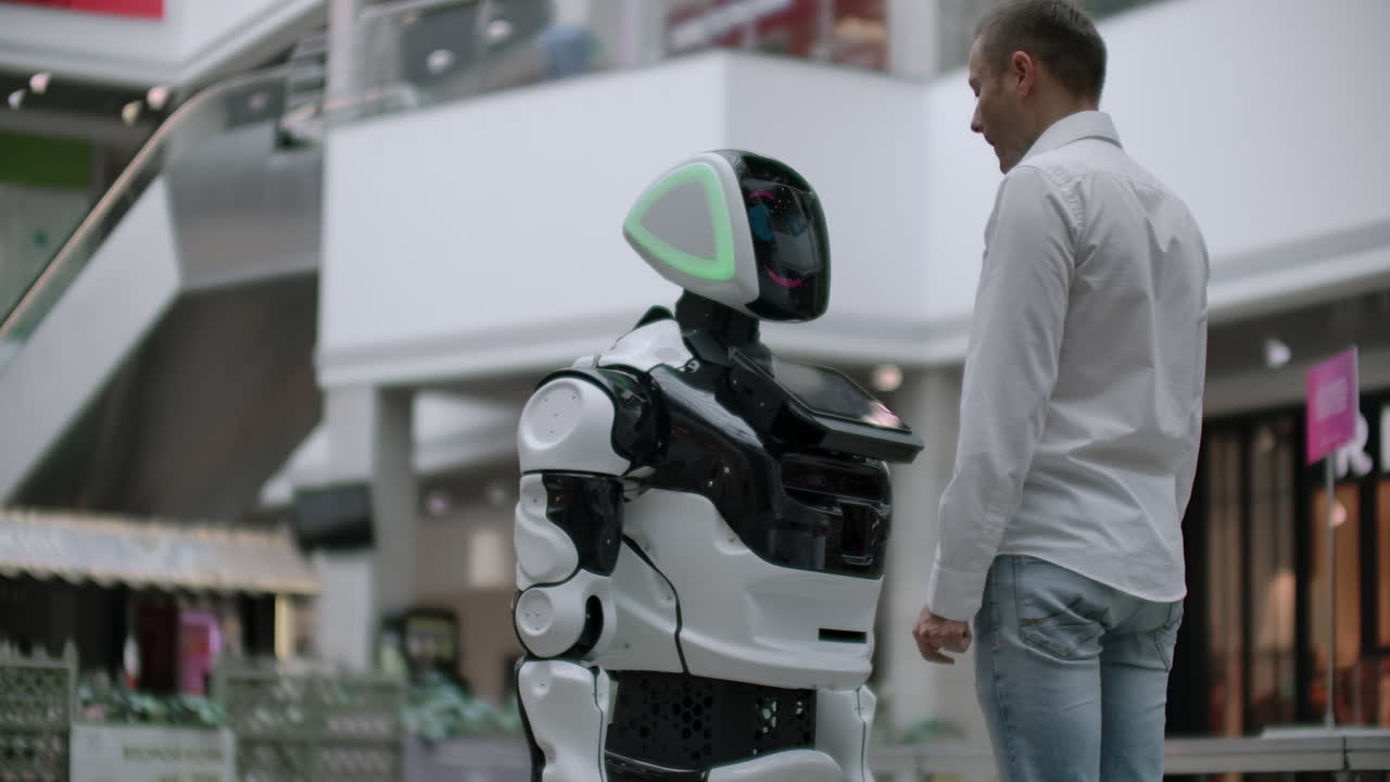 un hombre con una camisa se comunica con un robot blanco haciendo preguntas y presionando la pantalla con los dedos