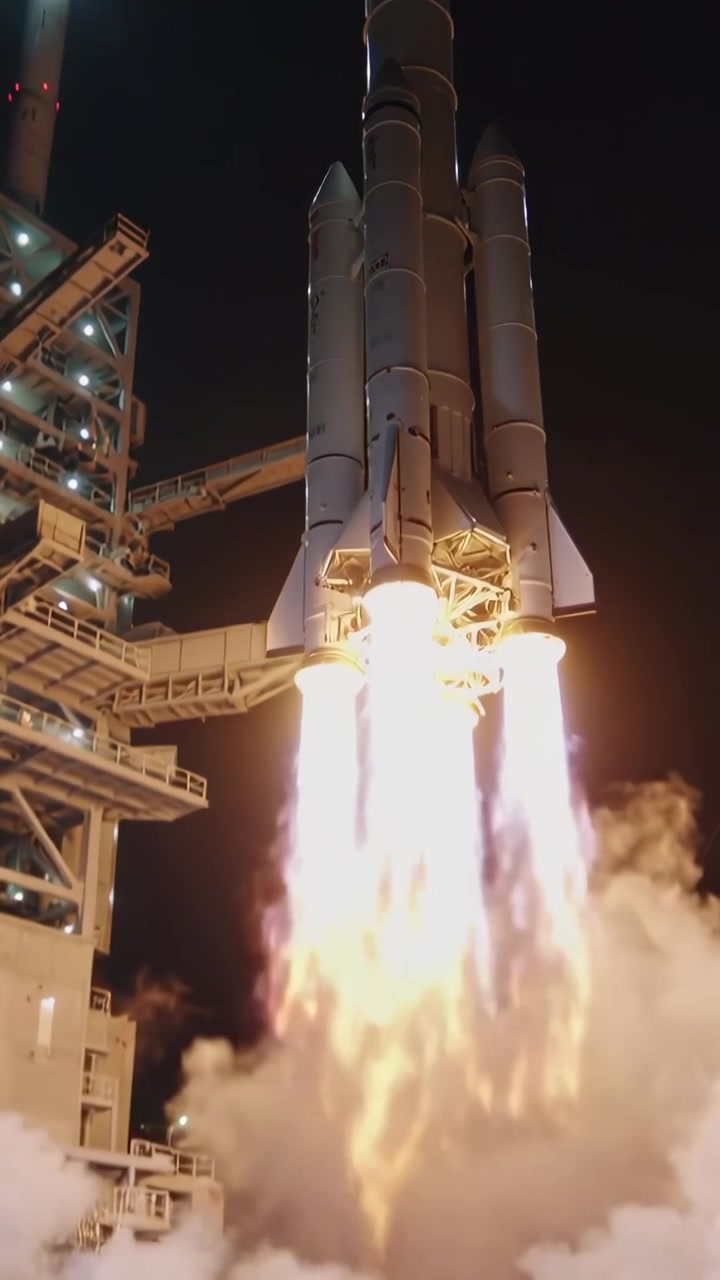 Vertical video: Igniting engines, large rocket lifting from night pad to reach orbit with gantry