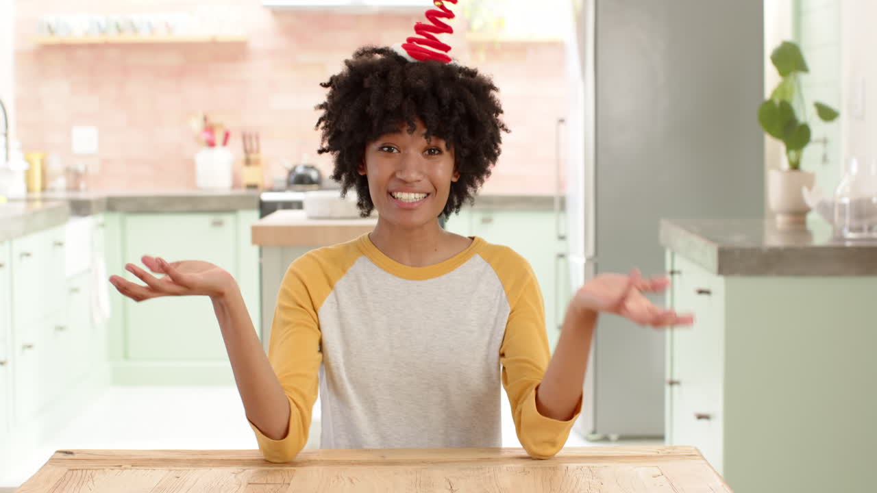 Wearing festive headband, woman sitting at kitchen table, embracing holiday spirit