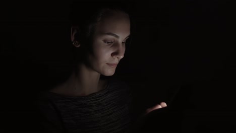 Closeup-view-of-a-woman-using-her-phone-in-a-dark-room,-chatting-in-the-darkness-with-smartphone,-communicating-with-friends-online