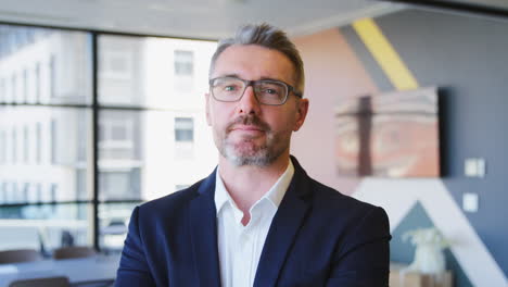 portrait of serious mature businessman wearing glasses  standing in empty office