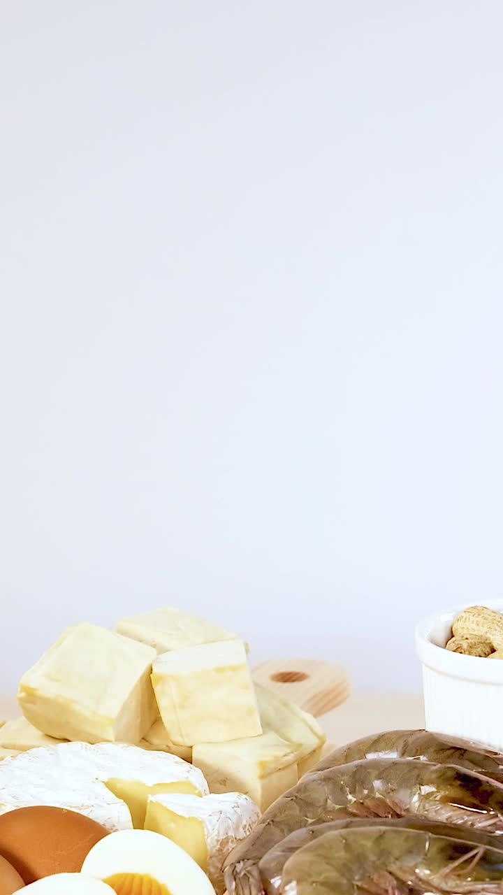 una variedad de alimentos ricos en proteínas, incluidas carnes, mariscos, lácteos y nueces, están ordenadamente dispuestos en una mesa