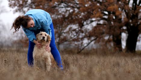 joyful young female petting her lovely dog outdoors