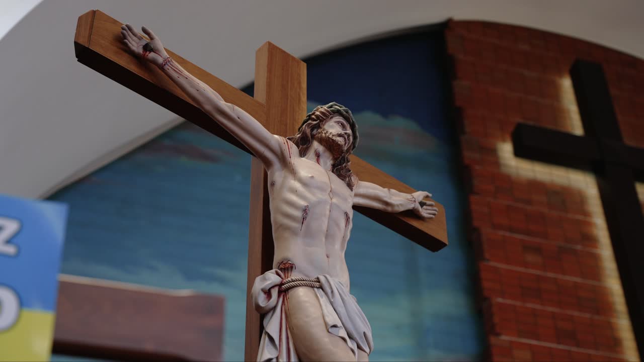 Close-up of a crucifix depicting Jesus Christ inside a church with a brick wall and cross in the background