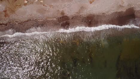 aerial birds eye view of sea waves breaking on sandy gravel beach in costa del sol