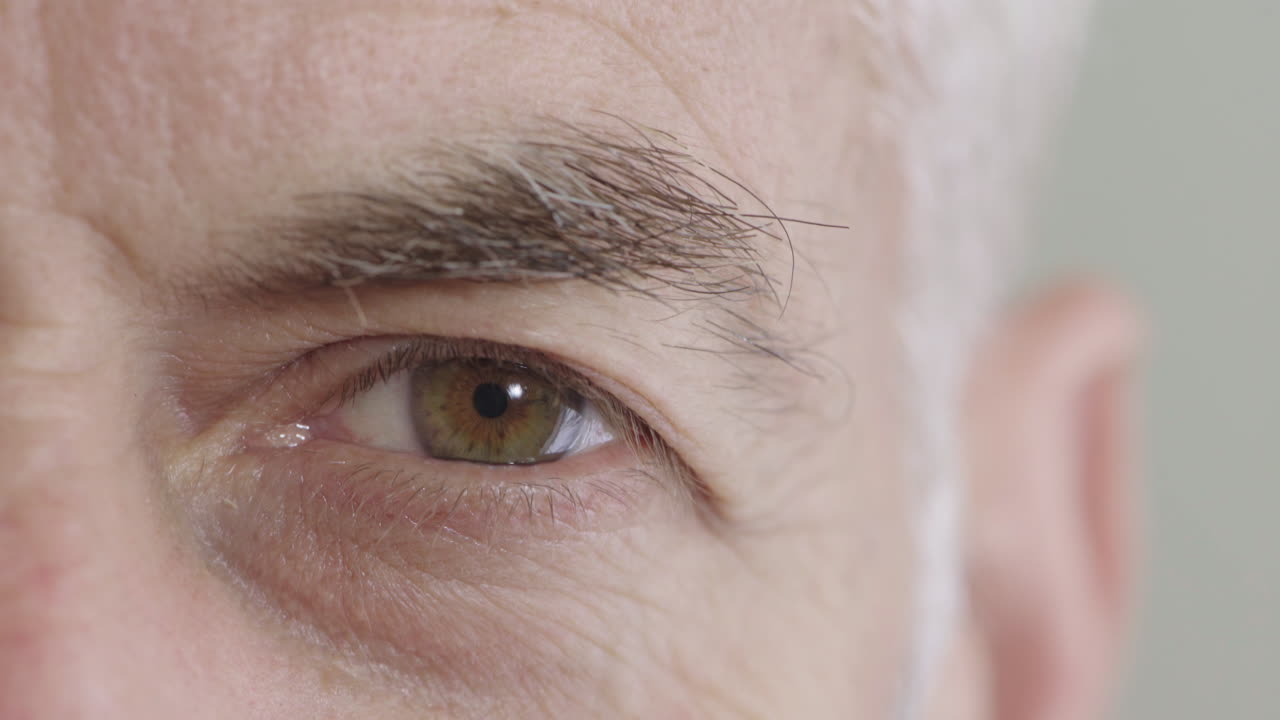 가까이 서 있는 중년 남자의 눈이 열리고 카메라를 보면서 노화된 주름을 보입니다.