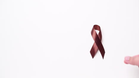 detail of male hand holding ribbon in brown color over white background