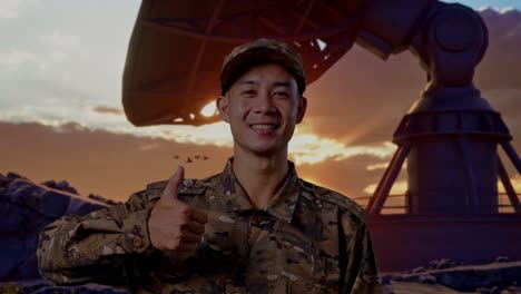 close up of asian man soldier smiling and showing thumbs up gesture while standing with satellite dish
