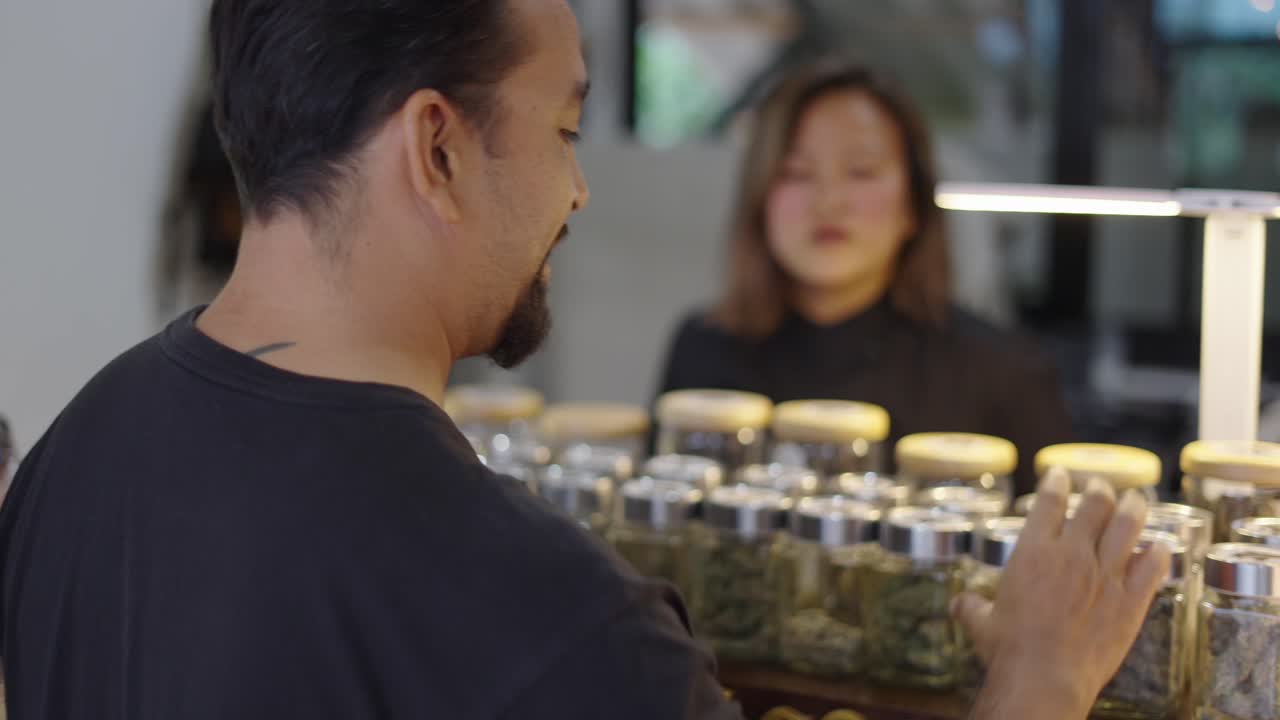 Man examining cannabis jars at a dispensary