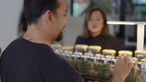 man examining cannabis jars at a dispensary