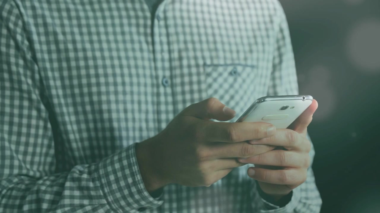 Uomo che tiene in mano uno smartphone bianco e tocca lo schermo, avviando grafici animati dell'interfaccia utente per una dimostrazione tecnologica.