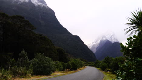 Winter-road-trough-snow-caped-mountains-in-Milford-Village-with-a-cloudy-blue-sky