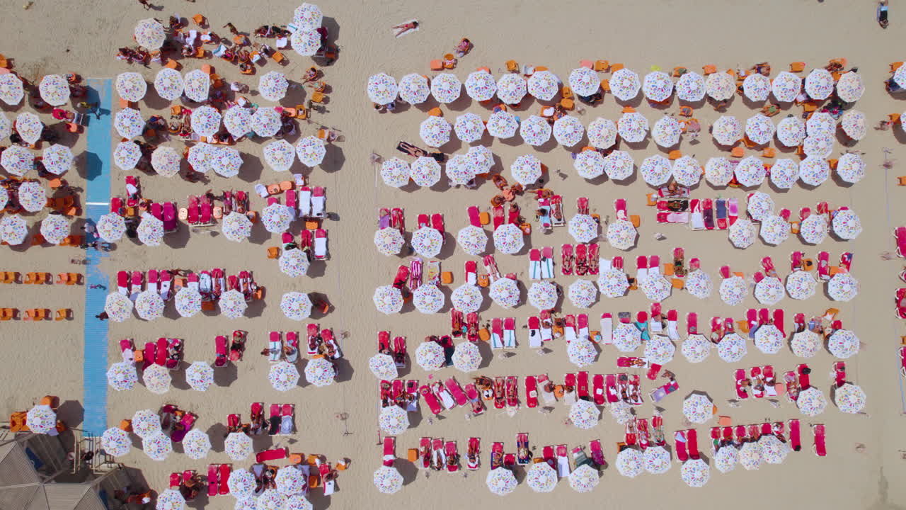 An abstract view of Tel Aviv, above the colorful beach umbrellas of the city's beaches with red sunbeds and orange plastic chairs - an ordinary summer day