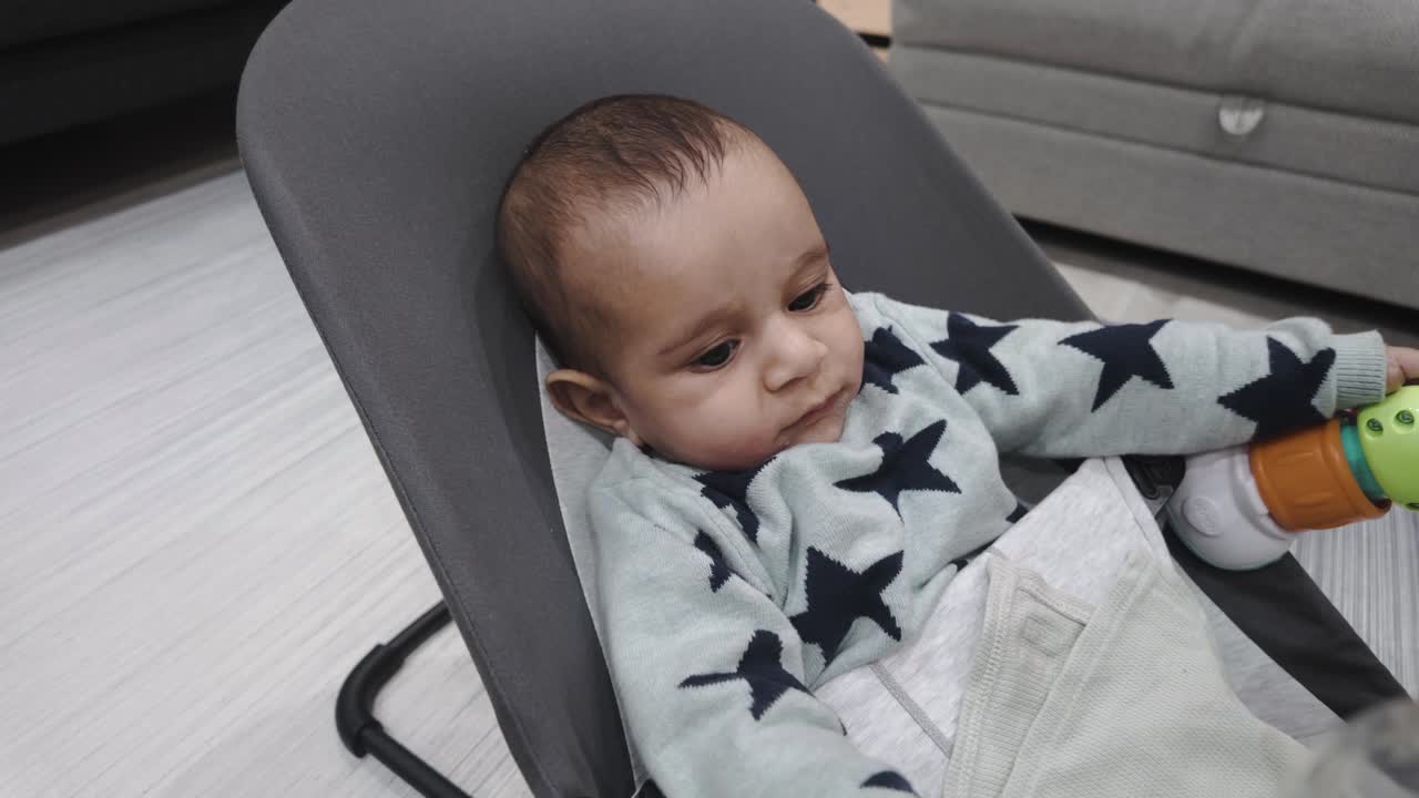 Adorable 4-month-old baby bouncer, holding onto cloth