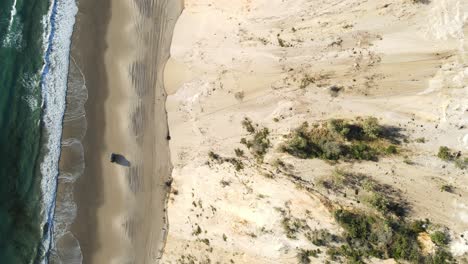 Looking-down-as-a-car-travels-alongside-the-ocean-on-a-beach-road-next-to-the-iron-rich-mineral-cliff-lines