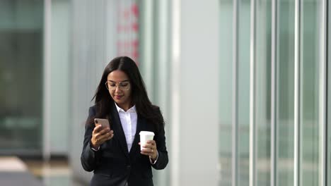 Smiling-Asian-woman-using-smartphone-during-stroll