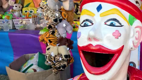 a vibrant clown head statue surrounded by an array of plush toys and colorful decorations.