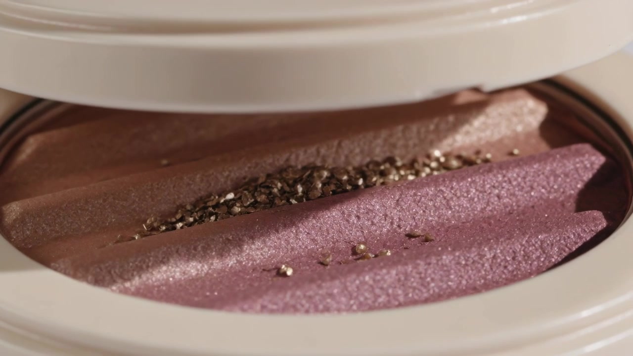 Falling gold flakes making compact 3-shade pan gathering in groove, lid lowering closing in studio