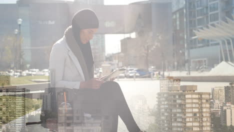 animation of asian woman in hijab using tablet over cityscape