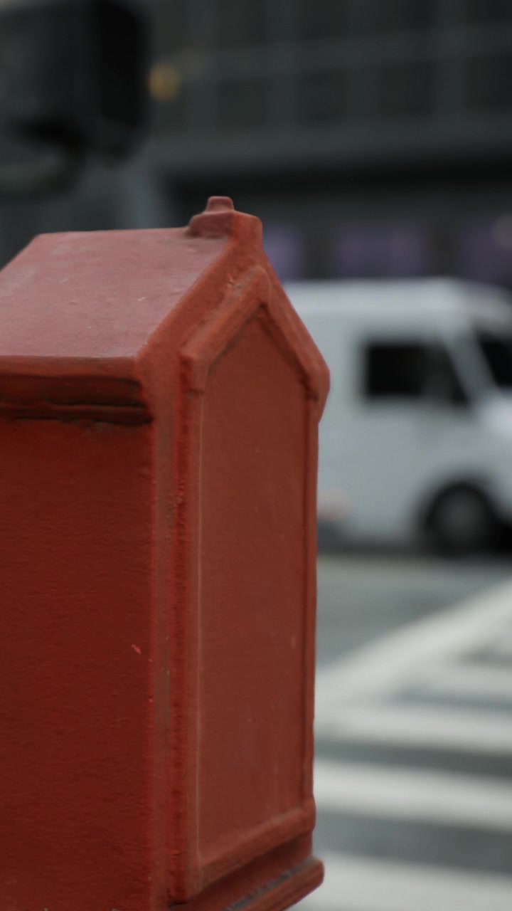 Una cassetta delle lettere rossa si trova vicino a un pedone che cammina in città di giorno
