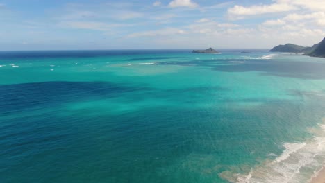 drone descends on hawaiian beach while turning to look at ocean with mini island in distance